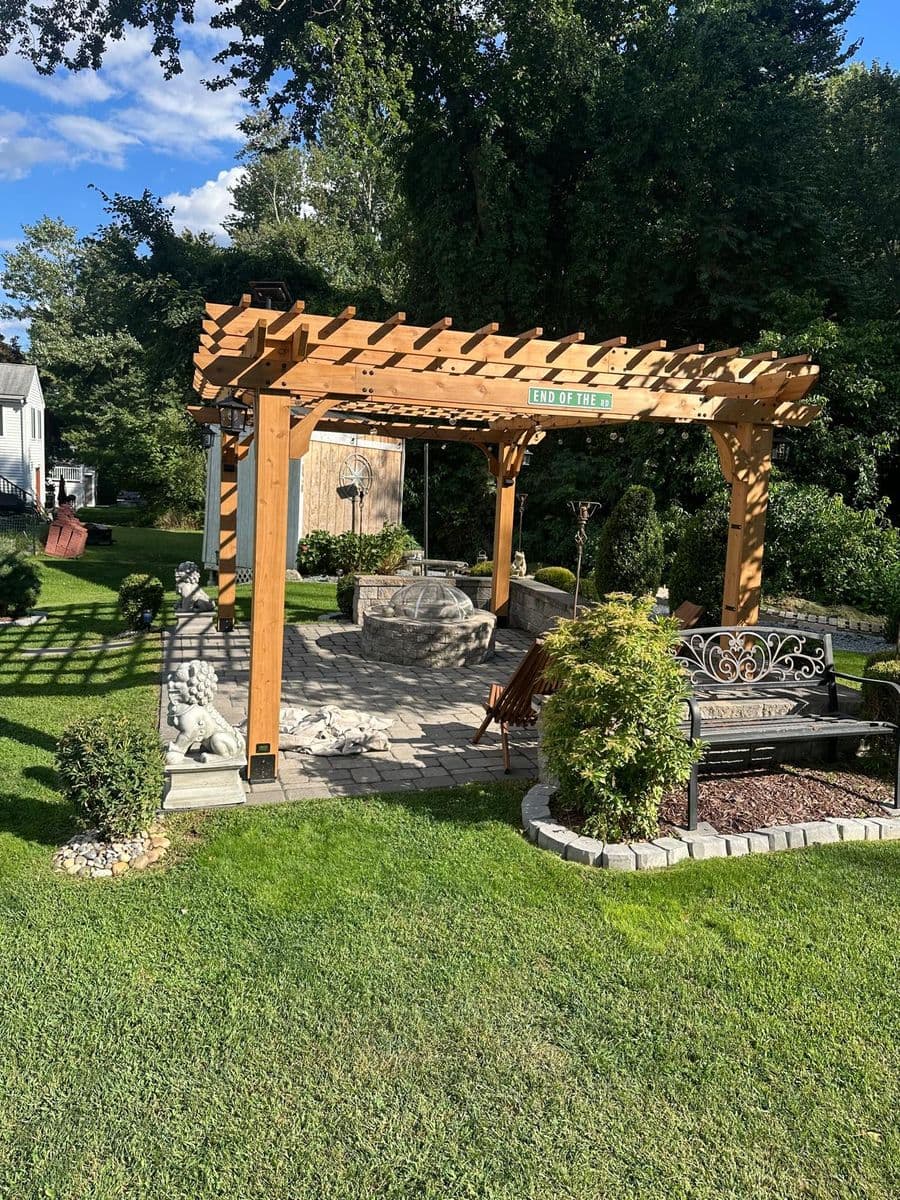 Cedar pergola with a stone fire pit and paver patio in a South Shore, MA backyard